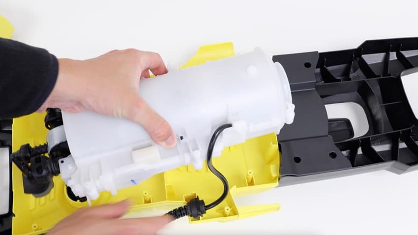 Hands installing a genuine spare part into an appliance